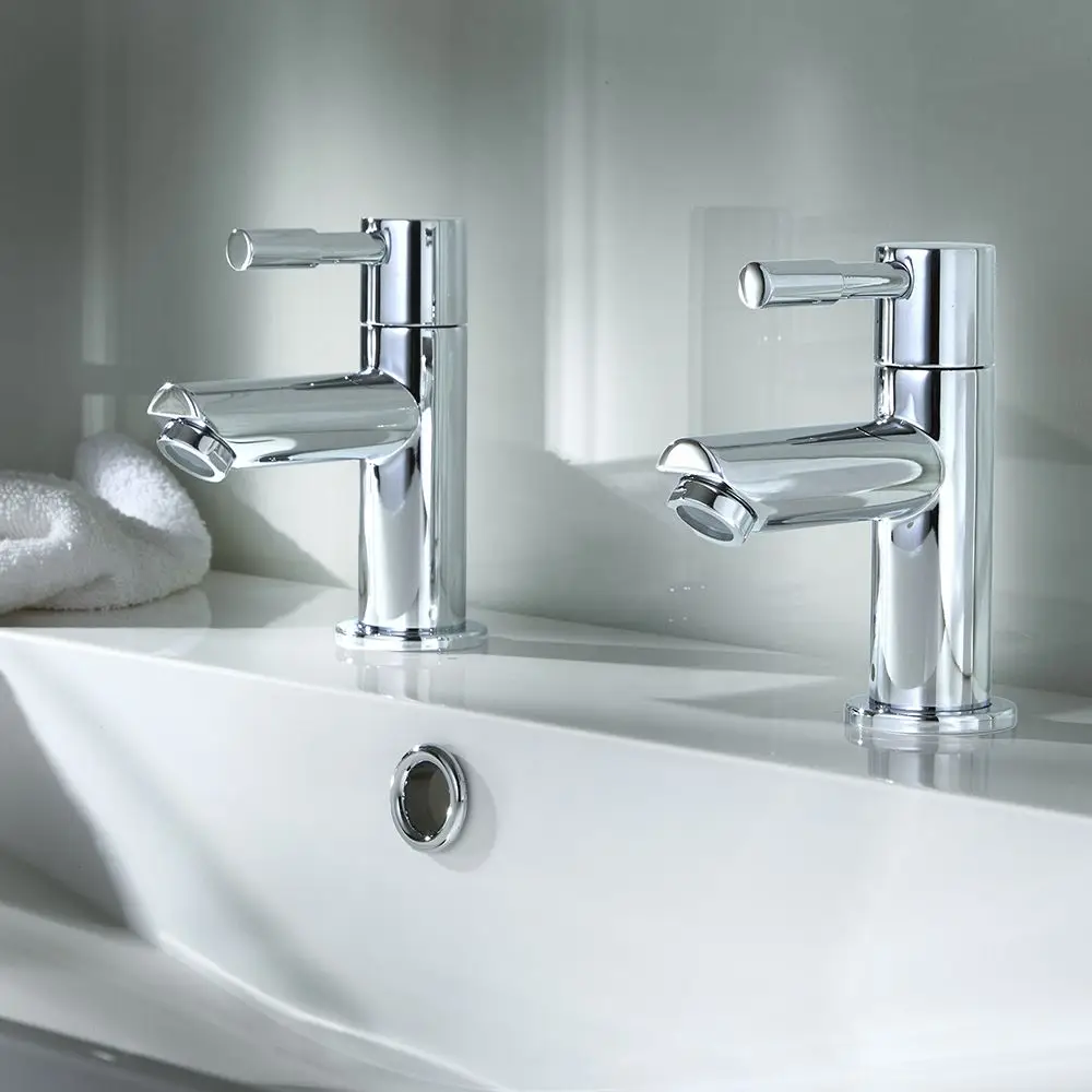 Two chrome bathroom sink faucets with lever handles mounted on a white sink.