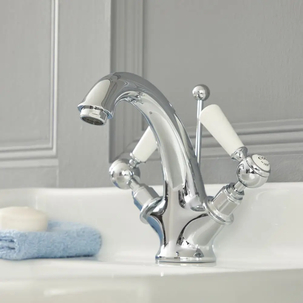 Chrome bathroom faucet with white ceramic handles and a sleek design mounted on a sink.