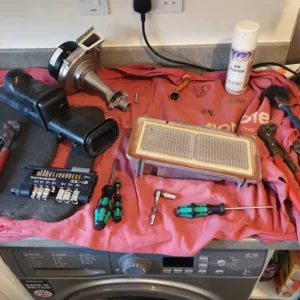 Various plumbing tools and equipment arranged on a work surface with a red cloth.
