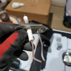 Hand holding a Vaillant boiler component with metal and ceramic parts.